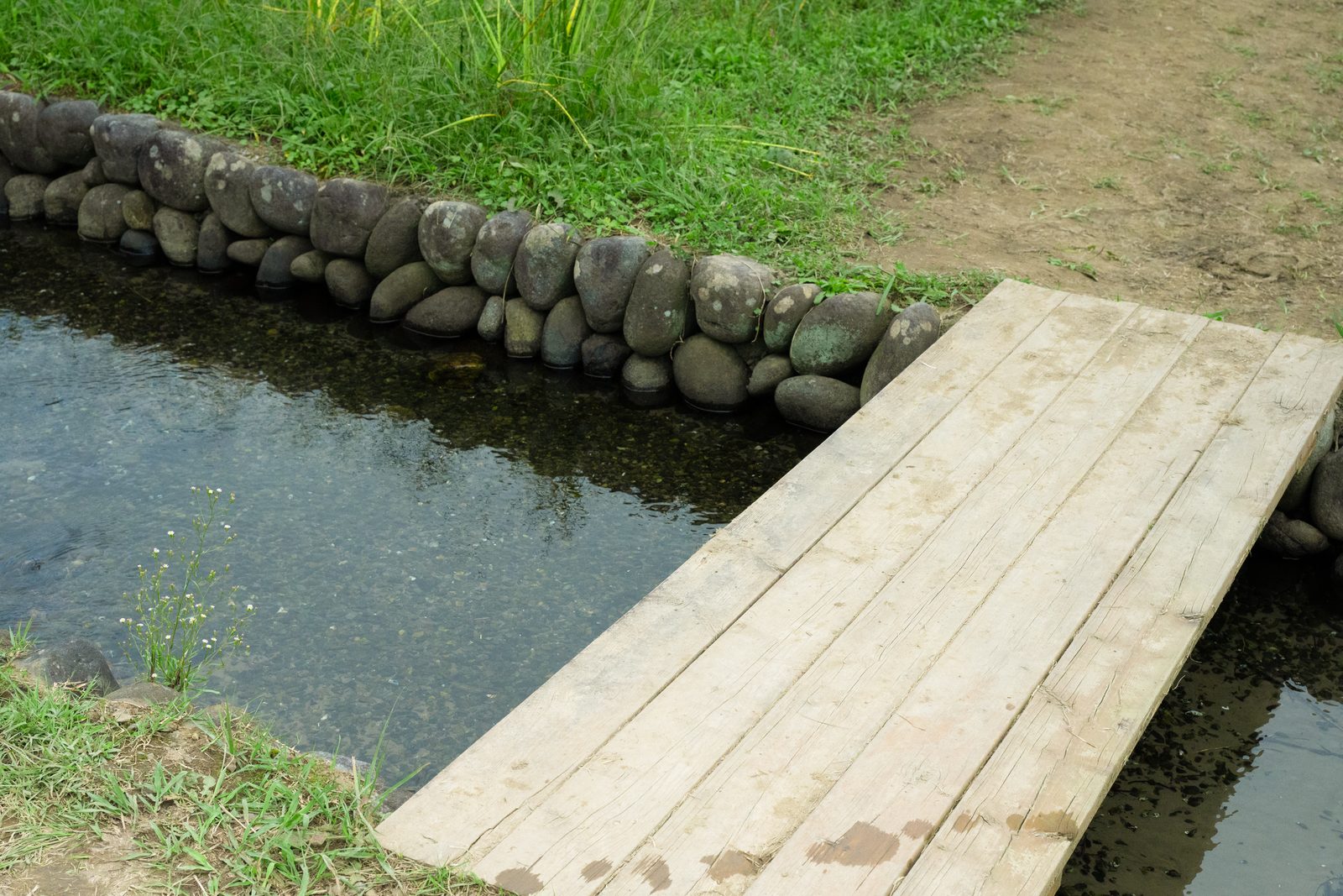 石積みの水路に架かる板の橋